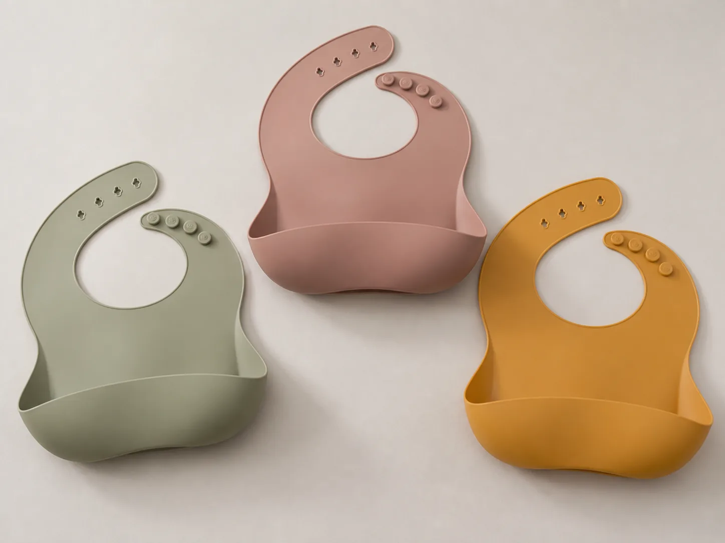 Three custom silicone baby bibs in sage rose and ochre color options
