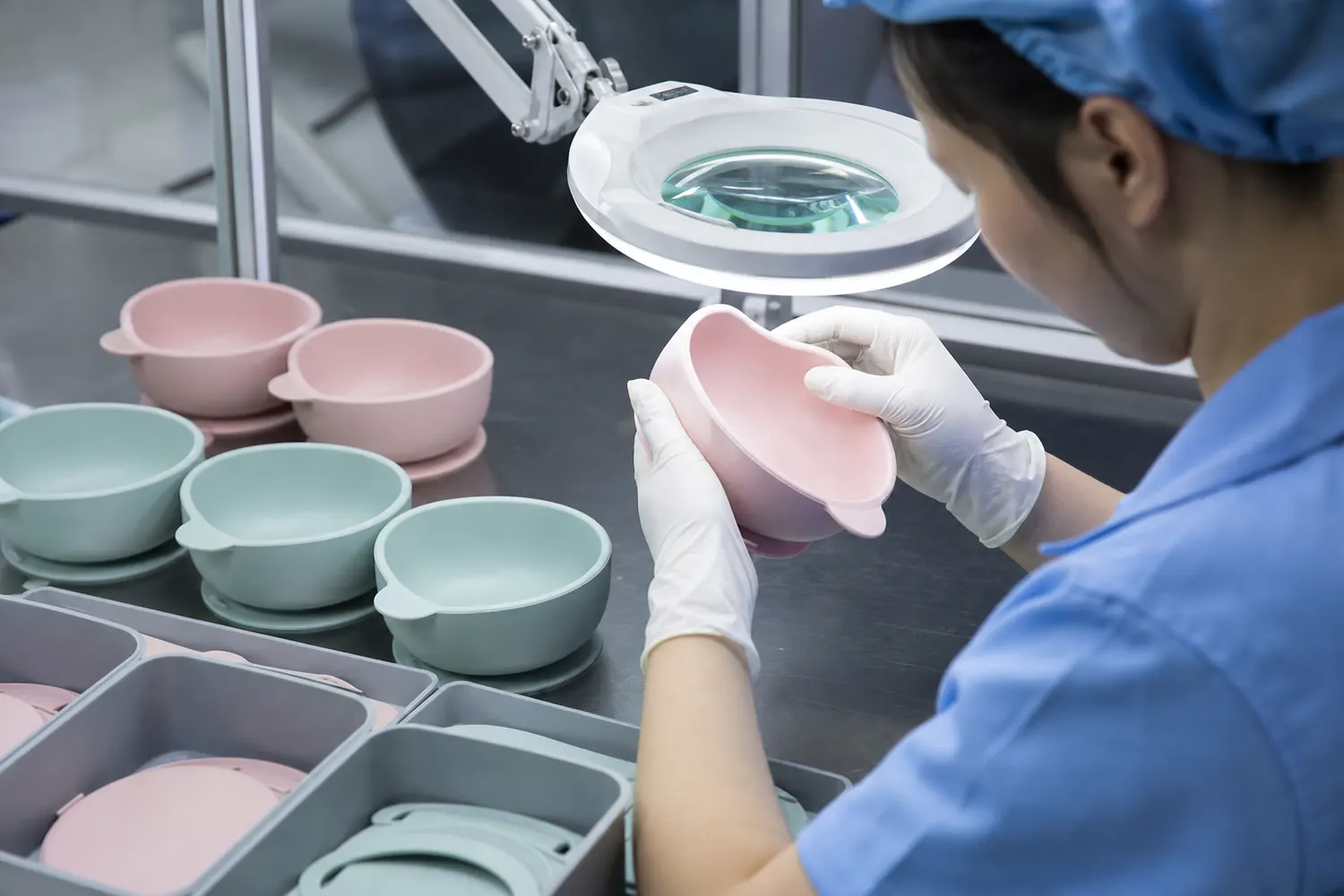 Inspector examining flash and parting line condition on custom silicone tableware under bright task lighting